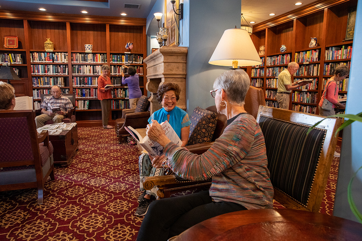 A senior man and woman sitting on a couch laughing together.